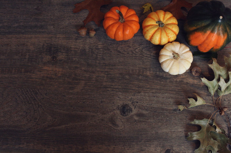 Fall Thanksgiving and Halloween pumpkins, leaves, acorn squash over dark wooden table background shot from directly above