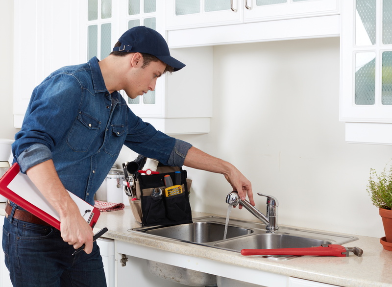 professional plumber doing reparation in kitchen home.